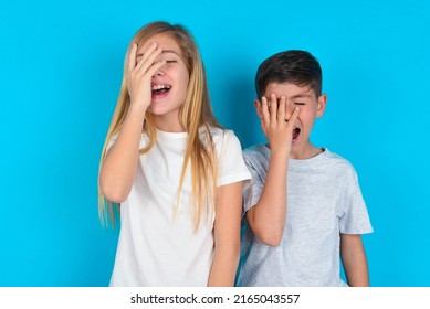 Charismatic Carefree Joyful Two Kids Boy And Girl Standing Over Blue Background Likes Laugh Out Loud Not Hiding Emotions Giggling Hear Funny Hilarious Joke Chuckling Facepalm.