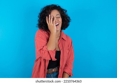 Charismatic Carefree Joyful Young Beautiful Woman With Curly Short Hair Wearing Red Overshirt Over Blue Wall Likes Laugh Out Loud Not Hiding Emotions Giggling Hear Funny Hilarious Joke Chuckling 