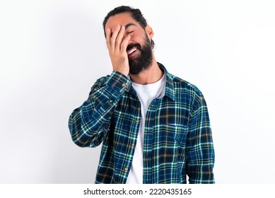 Charismatic Carefree Joyful Young Hispanic Bearded Man Wearing Plaid Shirt Over White Background Likes Laugh Out Loud Not Hiding Emotions Giggling Hear Funny Hilarious Joke Chuckling Facepalm.