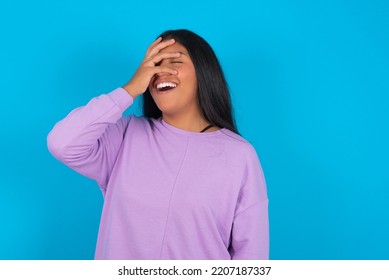 Charismatic Carefree Joyful Young Latin Woman Wearing Purple Sweatshirt Over Blue Background Likes Laugh Out Loud Not Hiding Emotions Giggling Hear Funny Hilarious Joke Chuckling Facepalm.