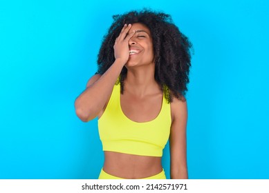 Charismatic Carefree Joyful Young Woman With Afro Hairstyle In Sportswear Against Blue Wall Likes Laugh Out Loud Not Hiding Emotions Giggling Hear Funny Hilarious Joke Chuckling Facepalm.