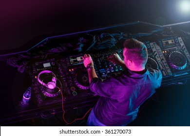 Charismatic disc jockey at the turntable. DJ plays on the best, famous CD players at nightclub during party. Selective focus. - Shutterstock ID 361270073