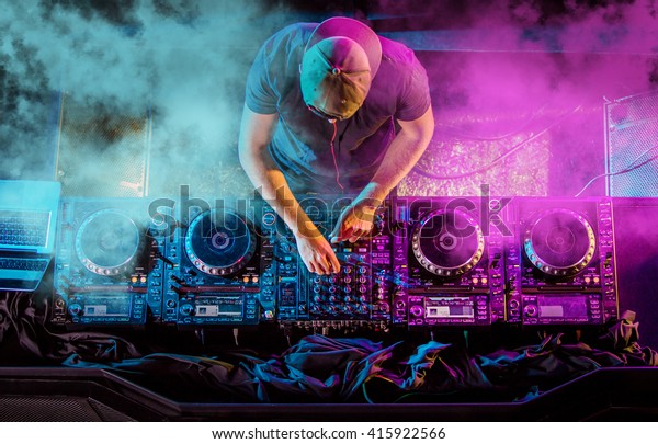 Charismatic disc jockey at the turntable. DJ\
plays on the best, famous CD players at nightclub during party.\
EDM, party concept.
