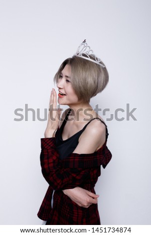 charismatic girl with short hair and a thin figure after a diet. a woman in a crown. street style clothing: men's plaid shirt and blouse with long straps.  