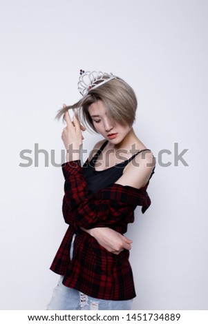 charismatic girl with short hair and a thin figure after a diet. a woman in a crown. street style clothing: men's plaid shirt and blouse with long straps.  