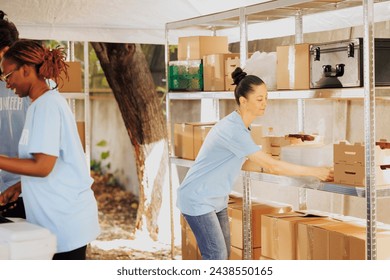 Charitable organization providing essential non-perishable items to refugees, offering a helping hand to the hungry and poor. Caucasian female volunteer organizes donation boxes for distribution. - Powered by Shutterstock