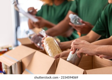 charity, donation and volunteering concept - close up of international group of happy smiling volunteers packing food in boxes at distribution or refugee assistance center - Shutterstock ID 2154594069