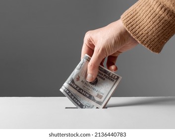 charity, financial support and saving concept - close up of hand putting money into donation box - Shutterstock ID 2136440783