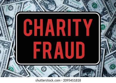 A charity fraud warning sign. In front of dollar bills. Scam and criminal concepts.