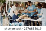 Charity organization shows devotion to fighting hunger and poverty by giving away free meals to homeless people. Warm food is provided by volunteers to caucasian wheelchair user and less privileged.