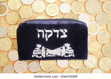 charity pocketbook with coins on a table. Hebrew text translation - Charity.