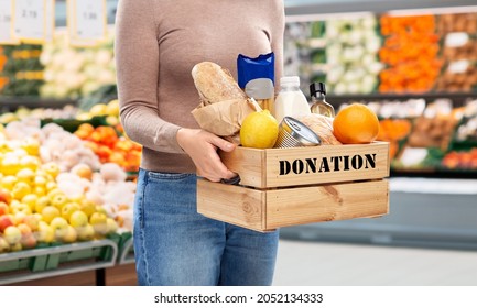 Charity, Relief Work And People Concept - Close Up Of Woman With Food Donation In Wooden Box Over Supermarket Background