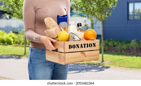 Charity, Relief Work And People Concept - Close Up Of Woman With Food Donation In Wooden Box Over City Street Background