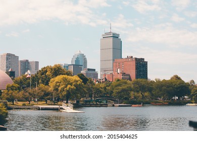 Charles River Esplanade in Boston Massachusetts lined with trees, a bridge across the water and city buildings in the background on a beautiful clear blue sky summer day.
