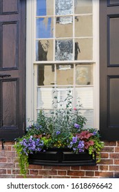 Charleston, SC - February 9, 2019: Abstract Reflections, Wavy Leaded Glass, And Colorful Winter Blooms Make An Attractive Streetside Display In The Historic District.