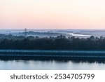 Charleston, SC, USA - The soft rays of the rising sun pierce through the mist hovering over the calm river and distant land. 