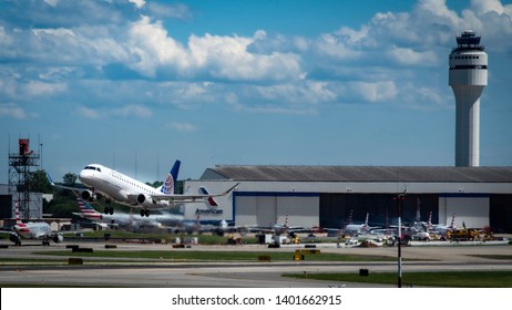 Charlotte, NC—May 13, 2019; Blue And White United Airlines Embraer ERJ 190 Takes Off What Other Planes Taxing, Hangers And Control Tower In The Background At Charlotte Mecklenburg (CLT) Airport.