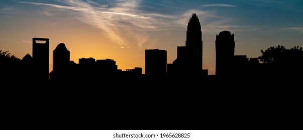 The Charlotte NC skyline silhouetted against the vibrant sky at sunset