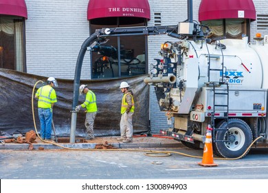CHARLOTTE, NC, USA-1/24/19: Three utility workers using a vacuum excavation truck in uptown Charlotte.