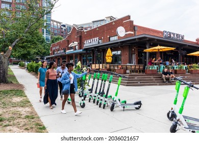 CHARLOTTE, NC, USA-25 JULY 2021: Group of four young women walking to Hawkers Asian Street Fare restaurant in South End, with people dining at outside veranda.
