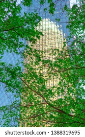 Charlotte, NC/USA - April 26, 2019:  Bright Crisp Colorful Blue And Green  Bank Of America Building Reflecting Off The Glass Of Another Building Looking Through Tree Branches In Uptown Charlotte, NC.