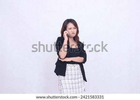 the charm of a beautiful Asian office woman in her 20s with a sullen expression while making a phone call on a cellphone gadget with her arms crossed isolated on a white background Foto stock © 