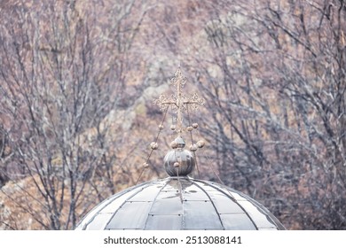 The charm of winter captivates as a church dome rises above a landscape of leafless trees, with a meticulously designed cross elegantly crowning its peak, evoking tranquility - Powered by Shutterstock