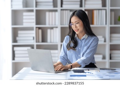 Charming asian businesswoman sitting working on laptop in office.