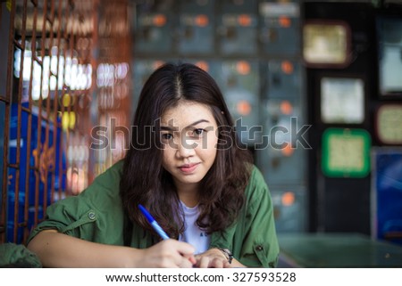 Charming asian girl sitting by wooden table and reading book outdoor education