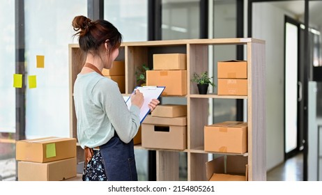 Charming Asian Millennial Woman Fashion Retail Shop Owner Checking Her Clothes And Accessories Stock In The Storage Room.