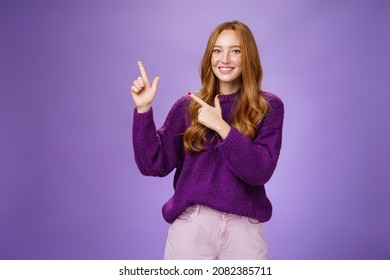 Charming Assertive Female Shop Assistant Pointing At Upper Left Corner To Promote Cool Product Smiling Broadly Feeling Joyful And Excited Expressing Friendly Attitude As Posing In Purple Sweater