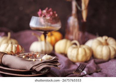 A charming autumn dining setting featuring white pumpkins, a folded linen napkin with dried florals, and a vintage glass, ideal for Thanksgiving dinner and seasonal table decor