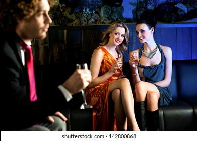 Charming Beautiful Girls Looking At Handsome Young Guy In A Bar.