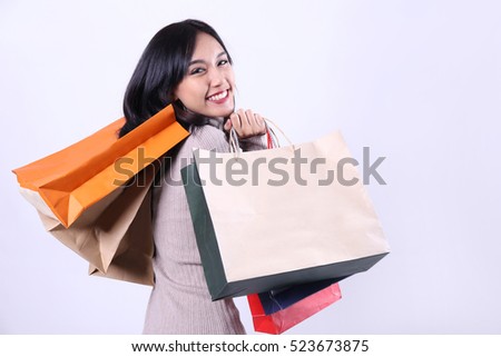 Charming beautiful tan skin Asian confident woman show shopping bags. Presenting your product. Shopping online shopaholic like weight lifting. Surprise discount price grand sale at new year festival.