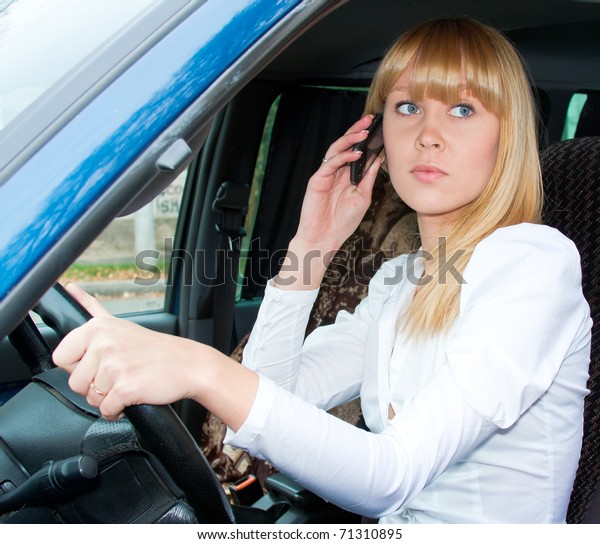 charming beautiful woman after the helm of car with\
a telephone in hands