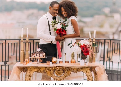 Charming black wedding couple holding handes on the terrace