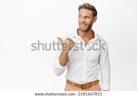 Charming blond guy pointing and looking left, smiling pleased, showing advertisement on copy space, white background