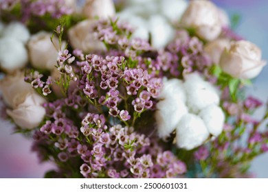 A charming bouquet featuring pink flowers and soft cotton stems arranged in a clear glass vase, placed on a windowsill. The soft natural light enhances the pastel tones of the flowers, creating a - Powered by Shutterstock