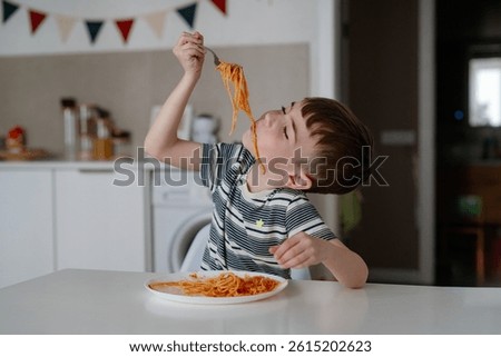 A charming boy eats spaghetti with tomato bolognese. A happy child eats freshly prepared healthy food indoors