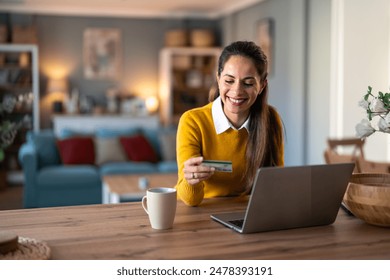 Charming businesswoman doing online shopping over laptop with credit card at desk in home office. - Powered by Shutterstock