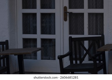 A charming cafe setting features a white gridpatterned door alongside several wooden chairs
