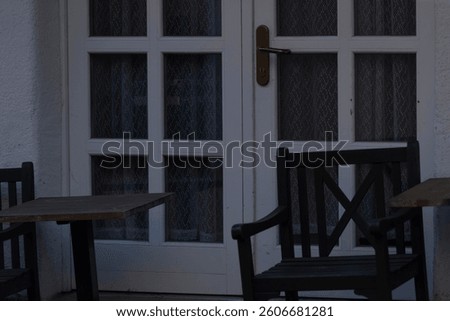 A charming cafe setting features a white gridpatterned door alongside several wooden chairs
