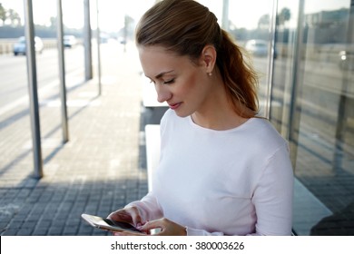 Charming Caucasian Female Watching Funny Video In Social Network Via Cell Telephone While Standing Outdoors In Summer Evening, Attractive Female Using Smart Phone While Waiting For A Bus On A Station 