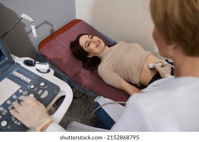 Charming Caucasian Woman Smiling At Her Attending Doctor While Checking Her Health During An Ultrasound Examination In A Medical Clinic. Ultrasonography USG