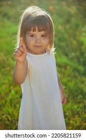 Charming Child In Linen Dress Walking On The Lawn