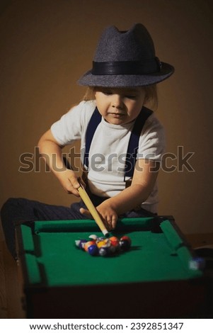 Charming child in retro clothes playing toy billiards