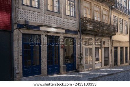 Charming cobbled alley with traditional Portuguese buildings, adorned with blue tiles and ornate metal balcony railings, reflecting the quaint and historic character of the city.