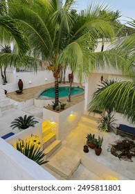  A charming courtyard featuring a pool surrounded by tropical plants and elegant decor, perfect for a luxurious and serene getaway.