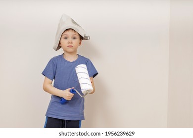 Charming Cute Little Emotional 5-year-old Boy In A Newspaper Hat Holds A White Roller In His Hands. сoncept Of Apartment House (renovation )