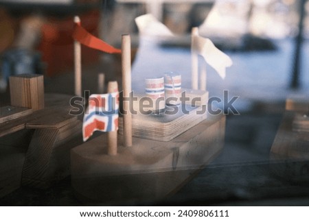 A charming and detailed image of miniature Norwegian boats and flags, reflected through a shop window in Norway, showcasing the country's rich maritime heritage and love for the sea.